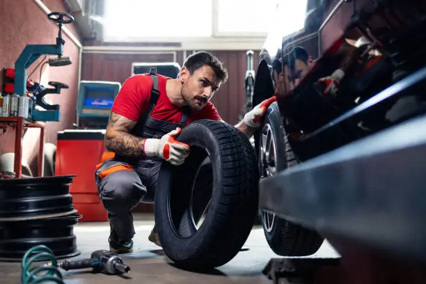 تبديل واصلاح الاطارات experienced tire repairman installing a new tire on a car.
